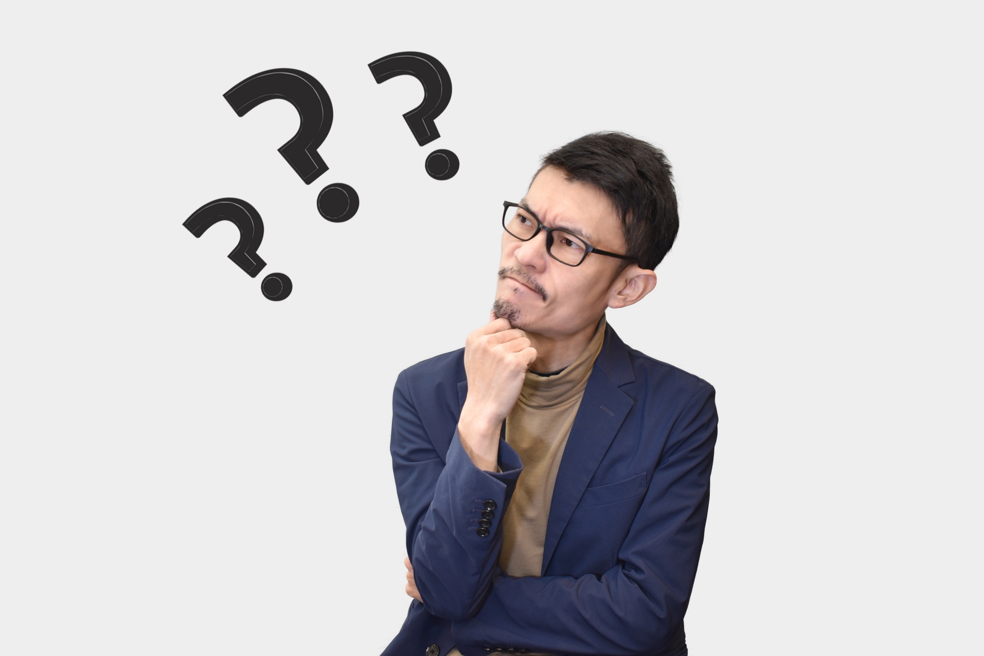 メガネをかけ、顎に手を当てて考え込む男性。頭上に3つの大きなクエスチョンマークがある。