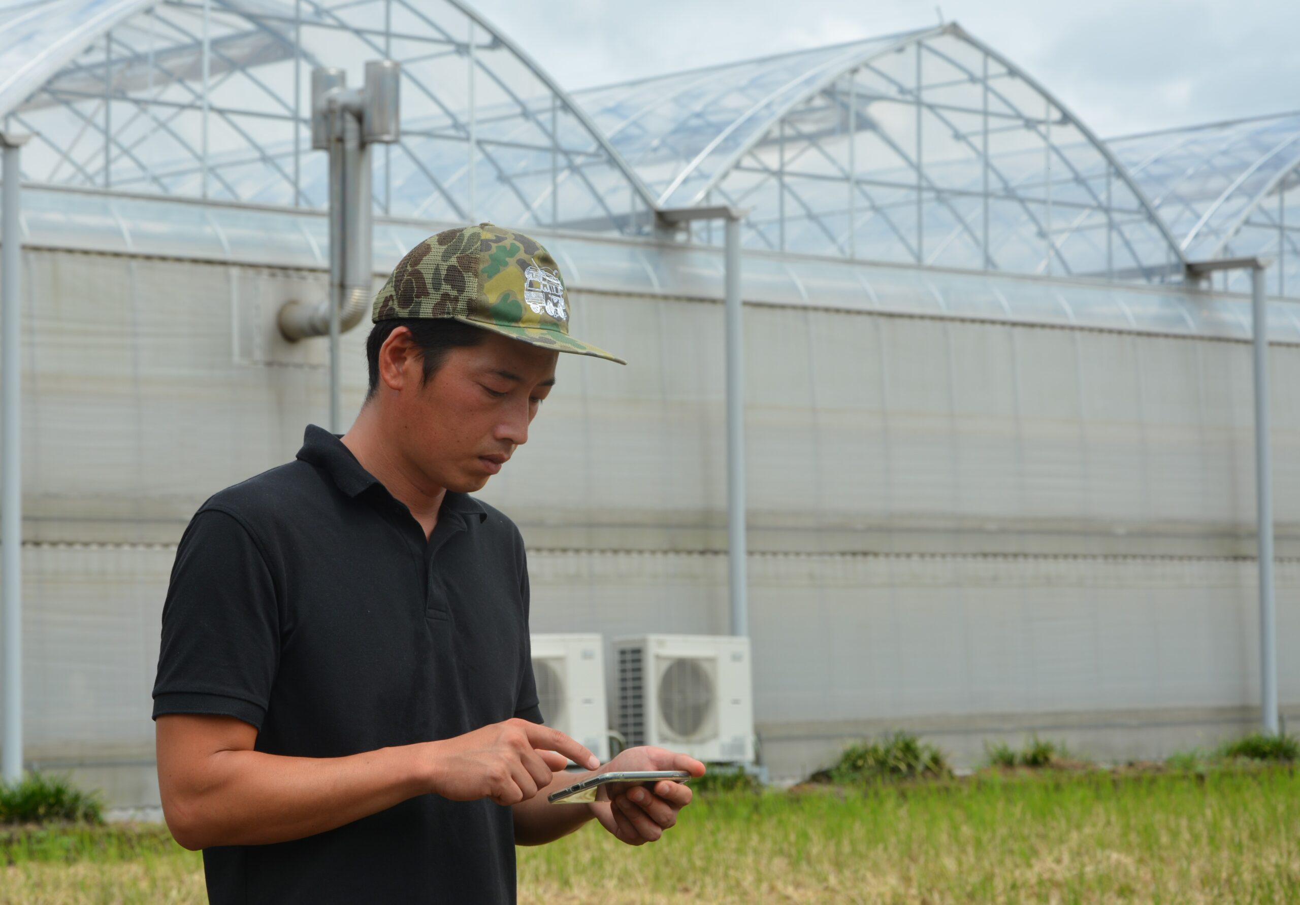 ハウスの外でスマホを操作している人