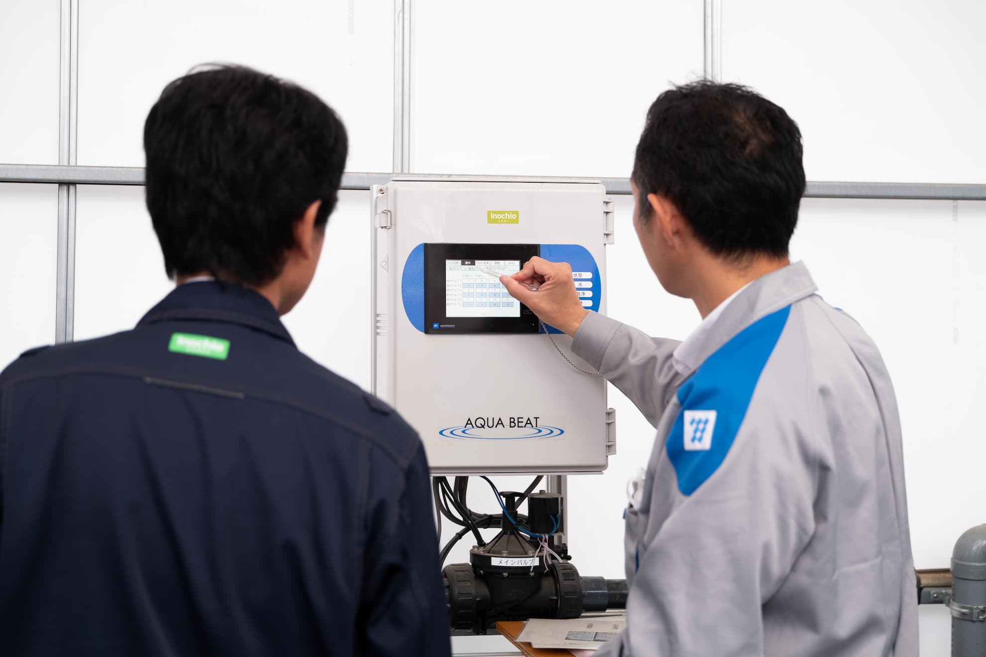 アクアビートEXの画面を見つめる作業着姿の二人